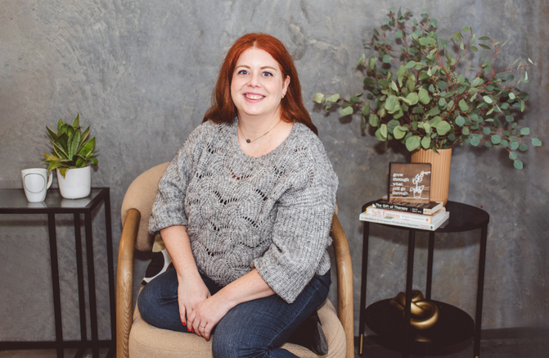Woman sitting in chair smiling calmly, representing support while learning how to stop overthinking