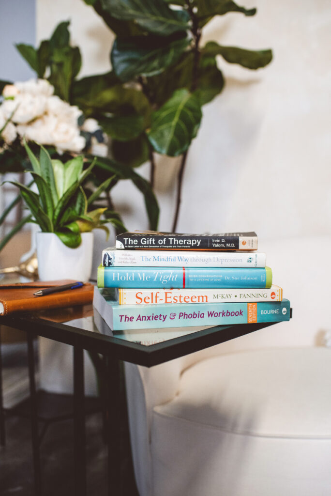 Therapy for perfectionism books on table with plants, calm space for reflection and support