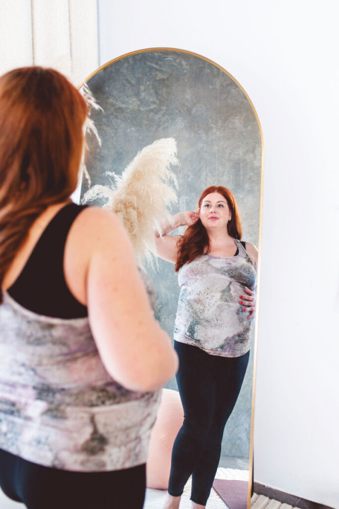 Woman looking at herself in mirror, reflecting on body image and mental health connection