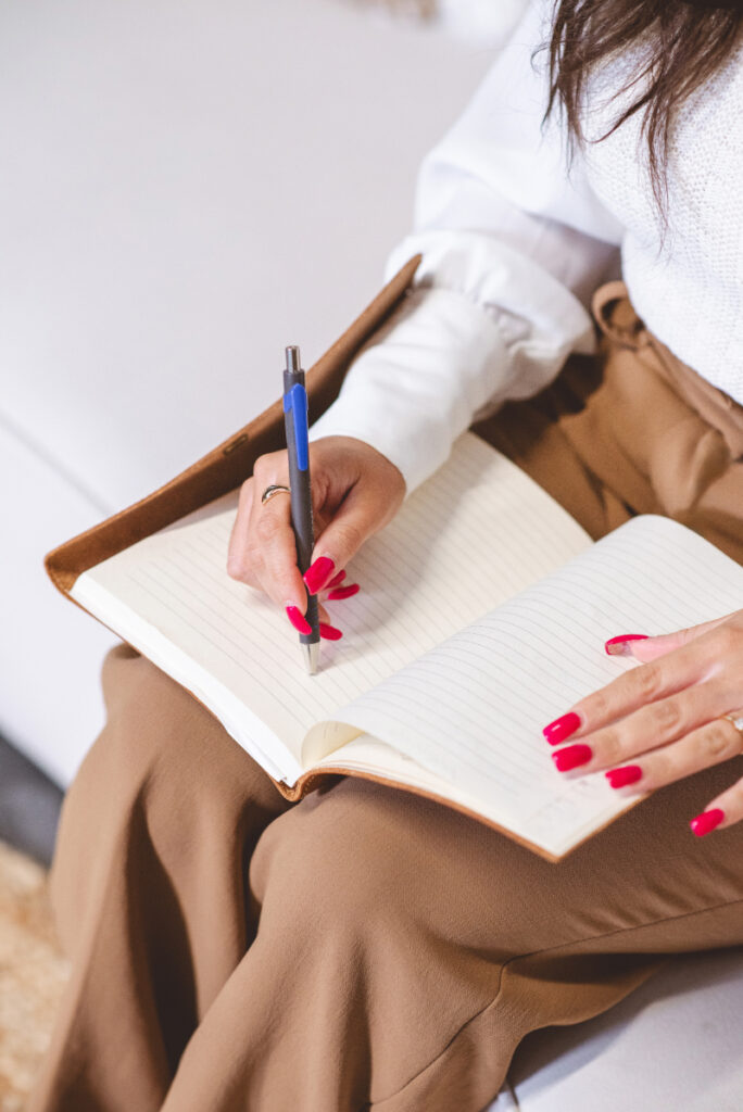 Person writing in a notebook while reflecting on ways to improve relationship communication skills.